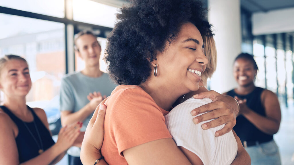 a person hugs another while others clap