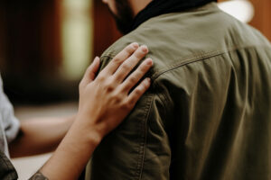 a person supporting another by touching their shoulder