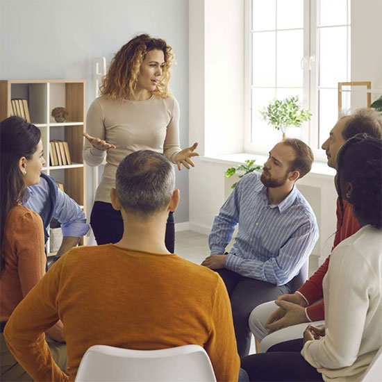 a person stands and speaks to a recovery group