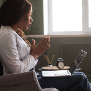 woman looking at computer and holding her hands together