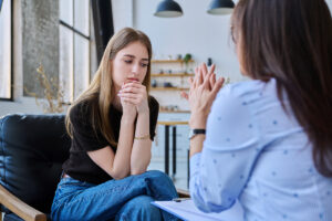 woman holding hands to face sits and listens to therapist talk in her marijuana addiction treatment