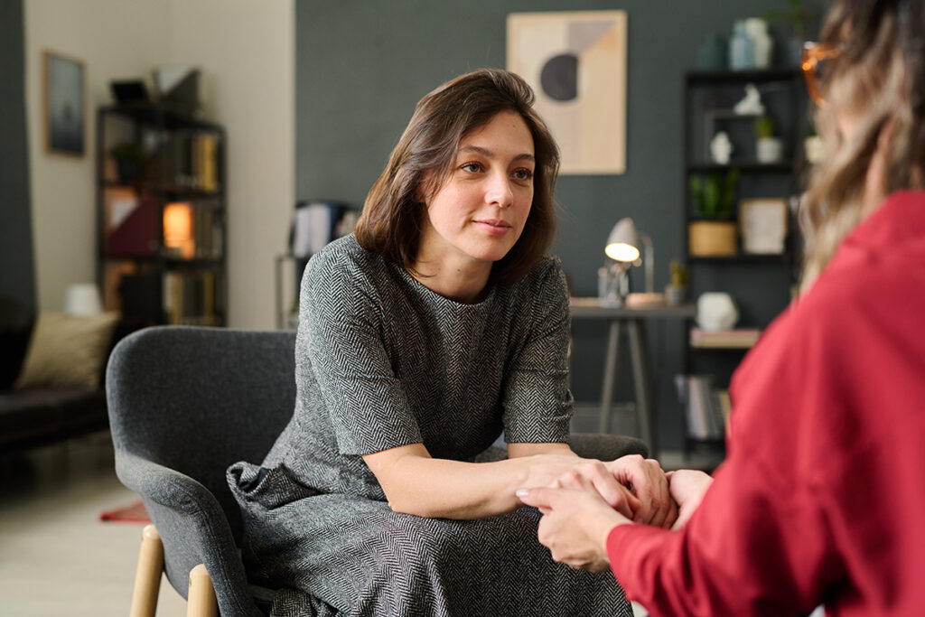 woman sits on couch talking to a friend about setting boundaries in recovery