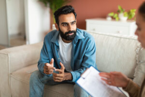 man sits on couch talking to a medical professional about the benefits of vivitrol