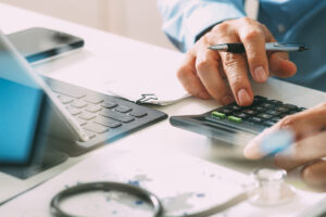 Closeup of someone calculating expenses on a calculator and tablet