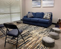 a therapy room at Sophros Recovery with floor pillows, a couch, and chairs